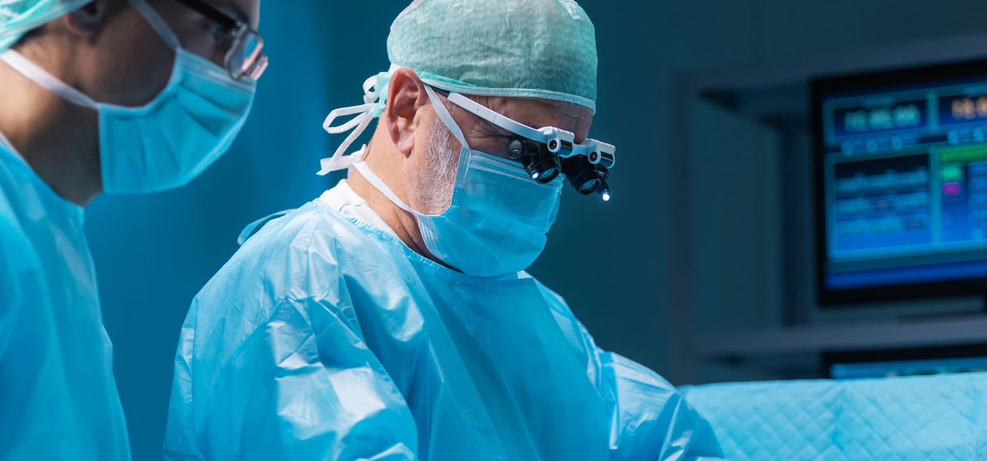 Two surgeons in scrubs and masks operating in a modern operating room